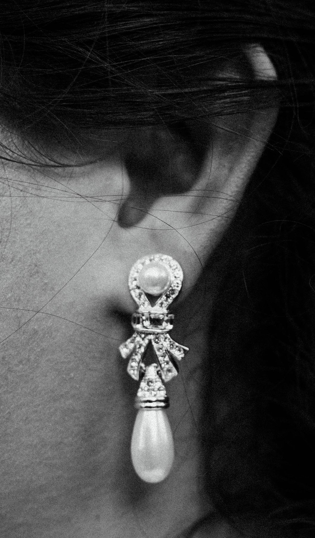 Black and white close-up of a bride's pearl and crystal drop earring.
