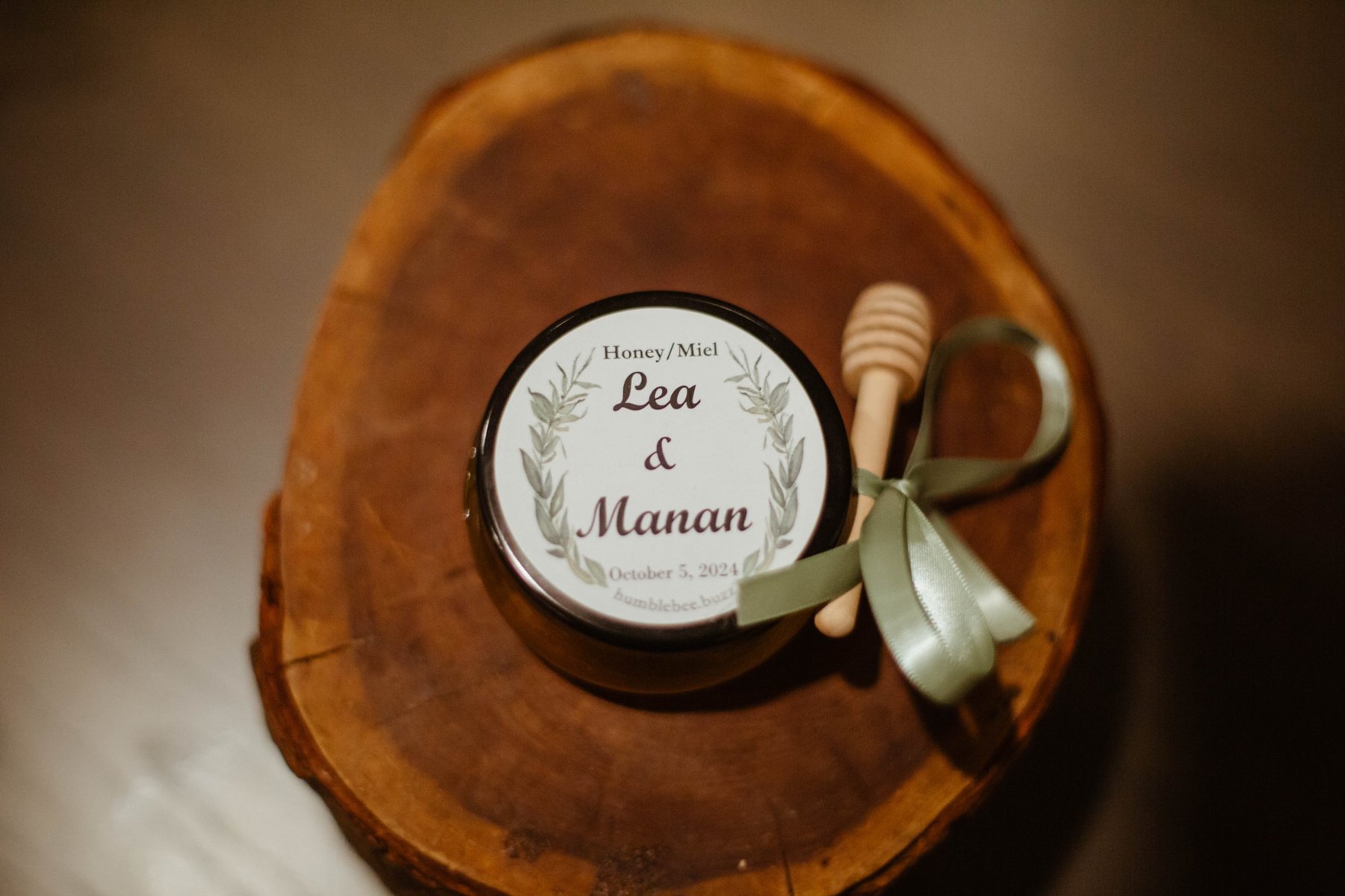 Close-up of a honey jar wedding favor labeled with the couple's names and wedding date.