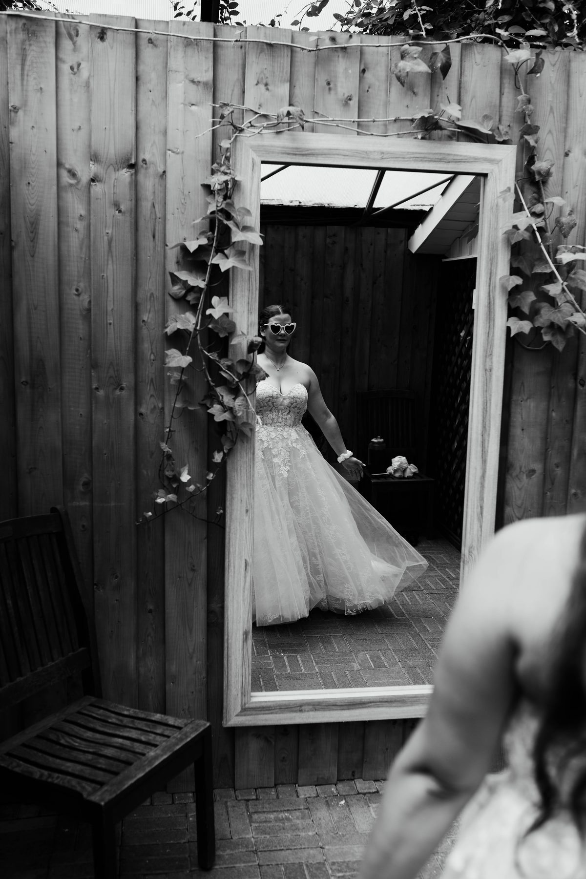 Black and white mirror reflection of a bride wearing heart-shaped sunglasses.