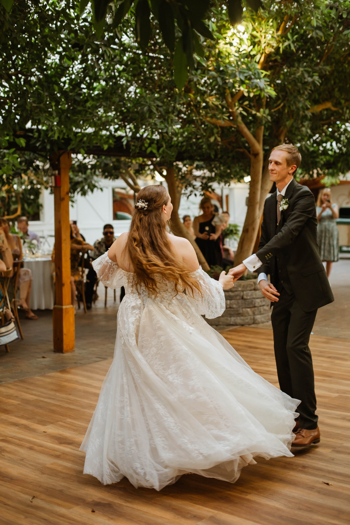 Bride and groom dancing together at their reception, both smiling.