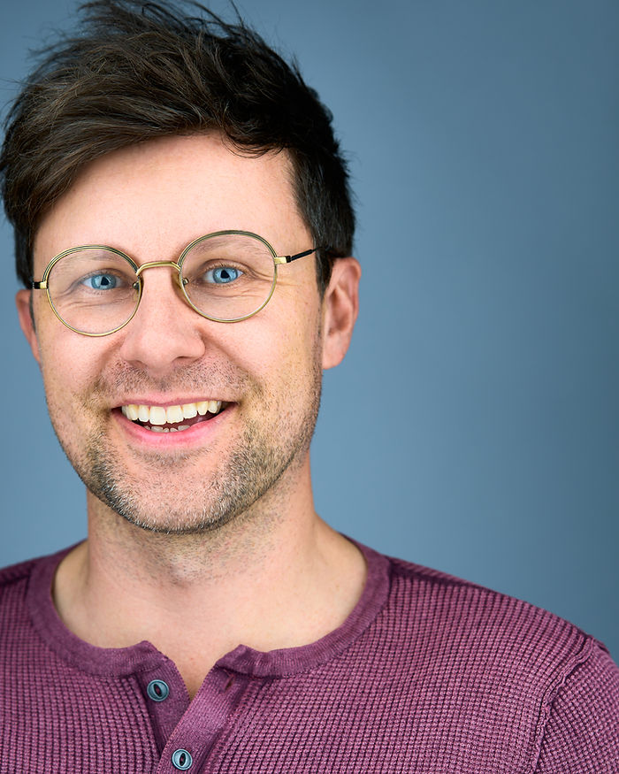 Portrait of Jason Wellings, wearing glasses and smiling.